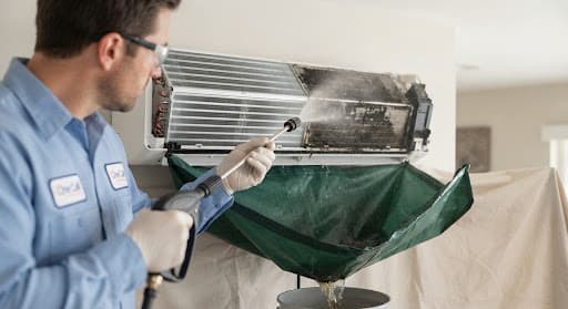 High-pressure jet cleaning the cooling coils of an AC unit